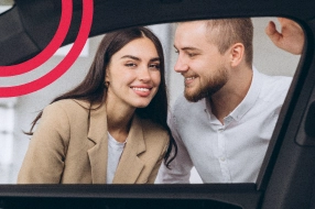 Casal sorrindo dentro de carro.