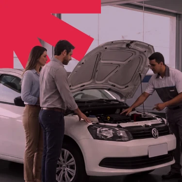Três pessoas em uma oficina automotiva analisando o motor de um veículo